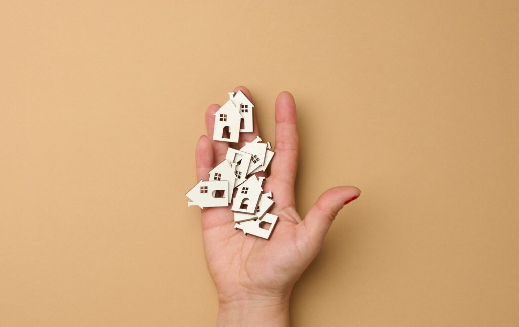 Woman's hand holds miniature wooden houses. Real estate search concept